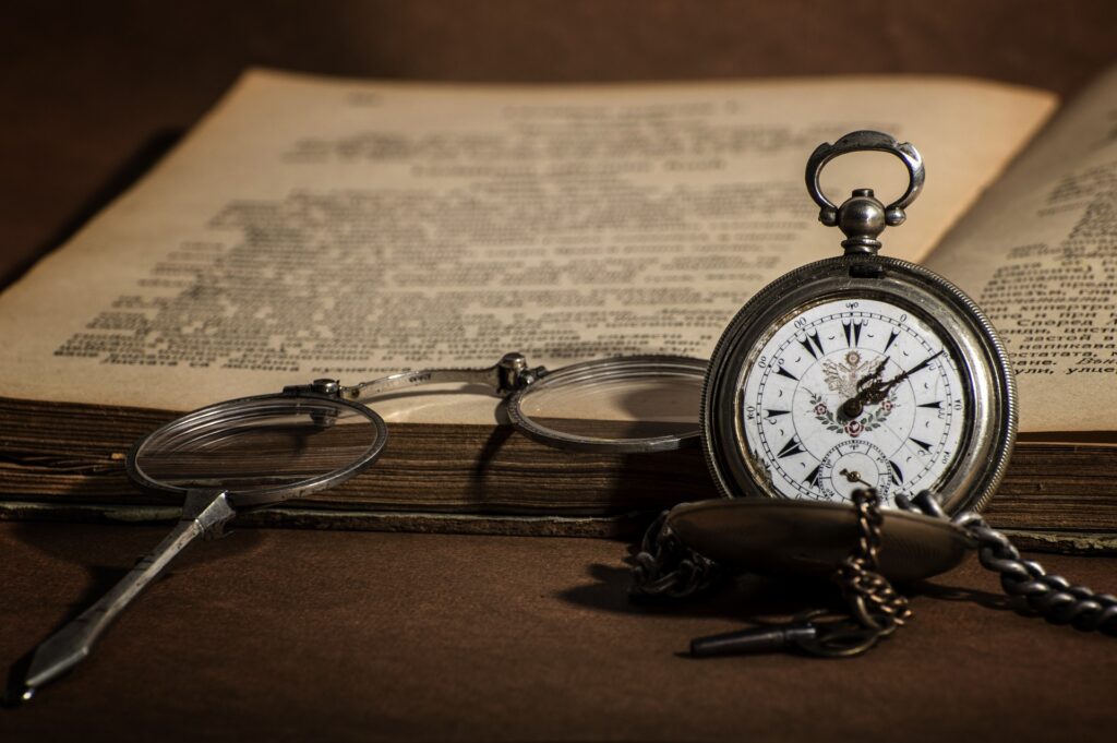 A photo of an open book, a watch and a glasses