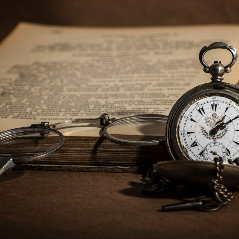 A photo of an open book, a watch and a glasses